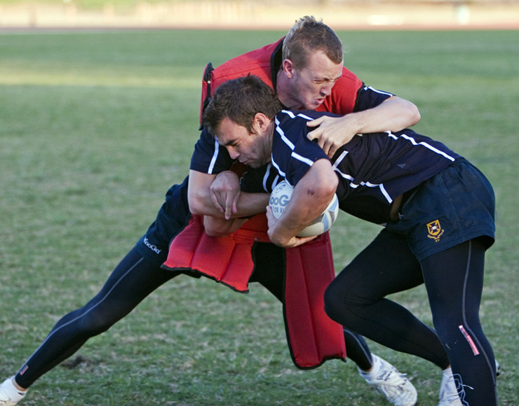 Two players tackling a rugby opponent.