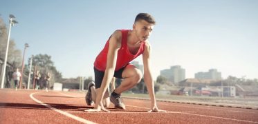 Young male athlete in start position on outdoor track, ready to sprint.