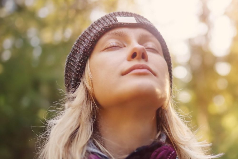 Woman outdoors with a beanie hat and eyes closed thinking